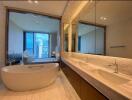 Modern bathroom with a freestanding bathtub, double sinks, and large mirrors