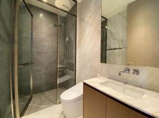 Modern bathroom with glass shower enclosure, sink and toilet