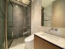 Modern bathroom with glass shower enclosure, sink and toilet