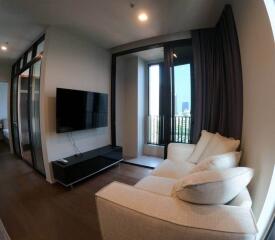 Modern living room with sofa, wall-mounted TV, and balcony access