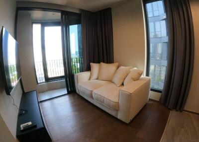 Cozy living room with a sofa, large windows, and a wall-mounted TV