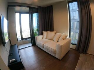 Cozy living room with a sofa, large windows, and a wall-mounted TV