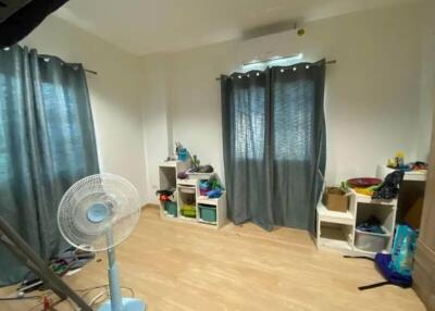 A bedroom with light wooden flooring, blue curtains, and shelving units.