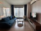 Modern living room with a blue couch, TV, floor-to-ceiling window, and city view