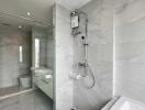 Modern bathroom with glass shower, bathtub, dual sinks, and gray tiles