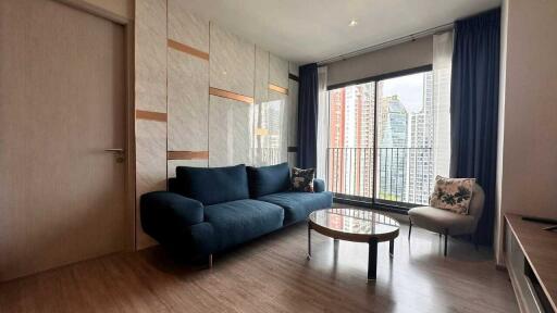 Modern living room with a blue sofa, glass coffee table, and large window with city view