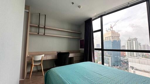 Bedroom with a bed, desk, chair, and city view