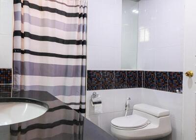 Modern bathroom with striped shower curtain and mosaic-tiled accents