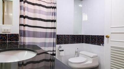 Modern bathroom with striped shower curtain and mosaic-tiled accents