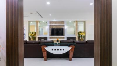 Modern living room with a large TV, brown leather sofas, and decorative flowers