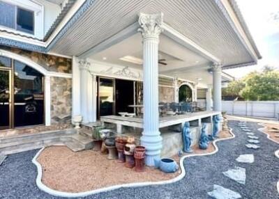 Exterior view of a house showing a patio with columns, decorative pots, and neatly arranged gravel landscaping