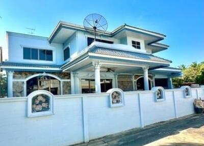 Two-story residential house with satellite dish on blue sky background