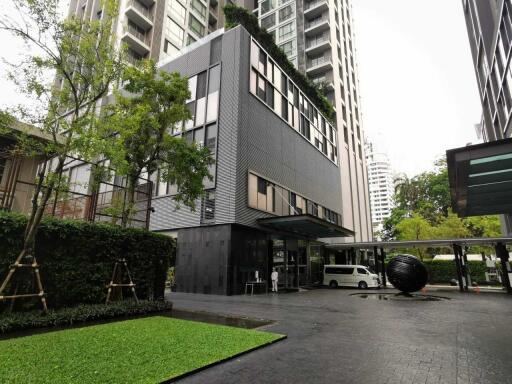 Modern high-rise building exterior with greenery and driveway