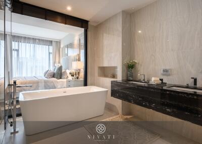 Modern bathroom with bathtub, double sinks, and a view into the bedroom