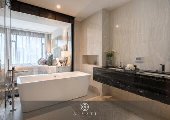 Modern bathroom with bathtub, double sinks, and a view into the bedroom