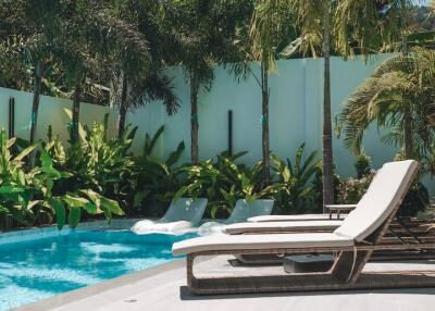 Luxury outdoor pool area with lounge chairs and palm trees