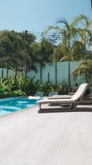 Luxury outdoor pool area with lounge chairs and palm trees