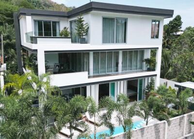 Modern three-story building with large windows and surrounding greenery