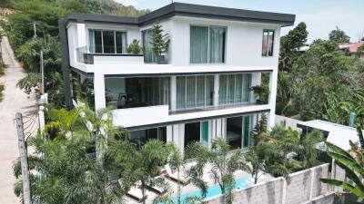 Modern three-story building with large windows and surrounding greenery