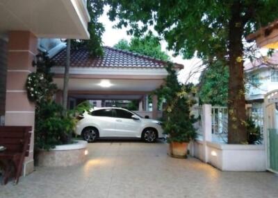 Carport area with trees and plants in front of the house