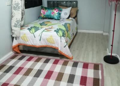 Small bedroom with colorful bedding and a checkered rug