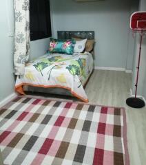 Small bedroom with colorful bedding and a checkered rug