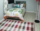 Small bedroom with colorful bedding and a checkered rug