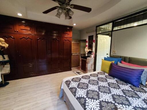 Spacious bedroom with wooden wardrobe and ceiling fan