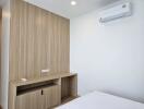 Modern bedroom with wooden built-in desk and air conditioning