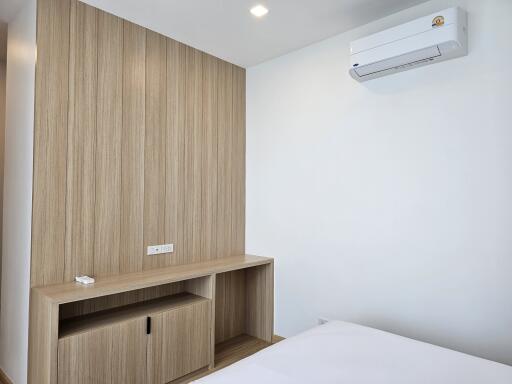 Modern bedroom with wooden built-in desk and air conditioning