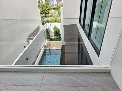 Glass balcony overseeing a pool and garden area