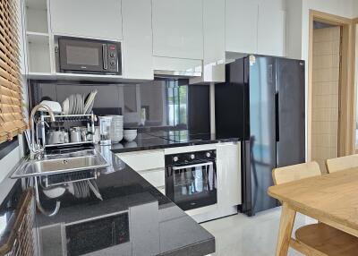 Modern kitchen with black countertops, white cabinets, and stainless steel appliances