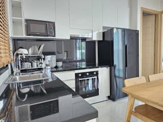 Modern kitchen with black countertops, white cabinets, and stainless steel appliances