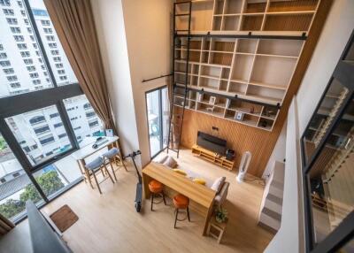 Loft-style living room with high ceiling and large windows.