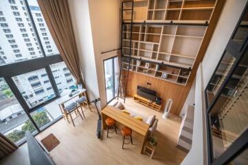 Loft-style living room with high ceiling and large windows.