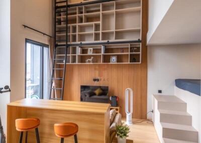 Modern living room with high ceilings, built-in bookshelves, and a loft area