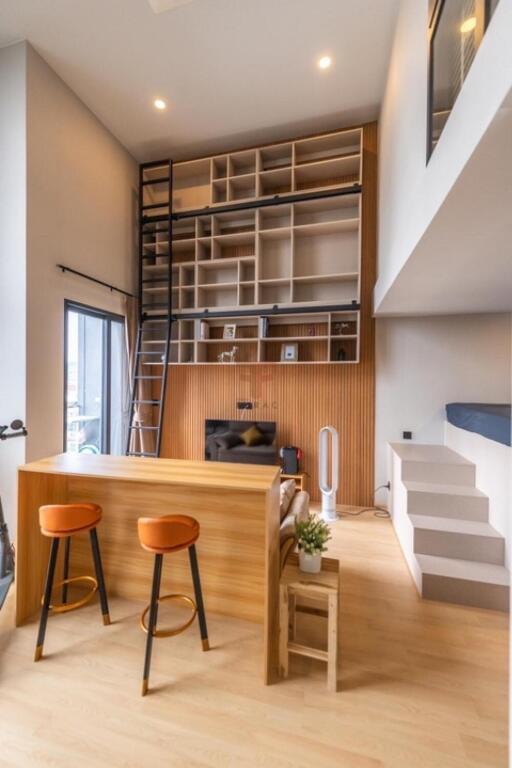 Modern living room with high ceilings, built-in bookshelves, and a loft area