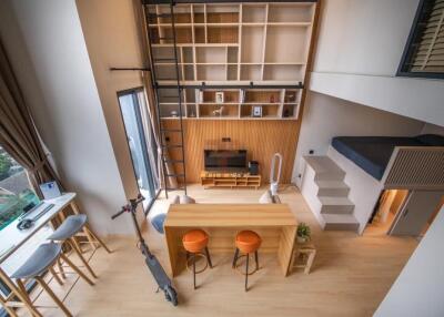 Modern loft-style living area with a mezzanine bed, kitchen island, and wall-mounted shelving.