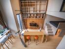 Modern loft-style living area with a mezzanine bed, kitchen island, and wall-mounted shelving.