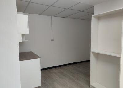 Minimalist kitchen space with ceiling tiles and shelving