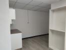 Minimalist kitchen space with ceiling tiles and shelving