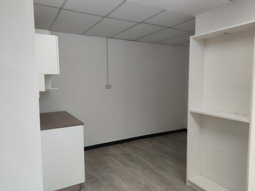 Minimalist kitchen space with ceiling tiles and shelving