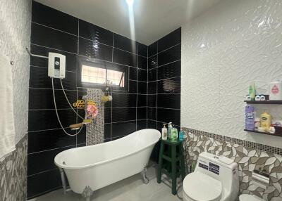 Modern bathroom with black and white tiles, bathtub, and toilet