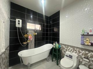 Modern bathroom with black and white tiles, bathtub, and toilet