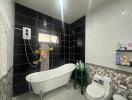 Modern bathroom with black and white tiles, bathtub, and toilet