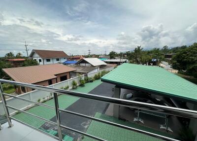 Outdoor view with rooftops, greenery, and carport