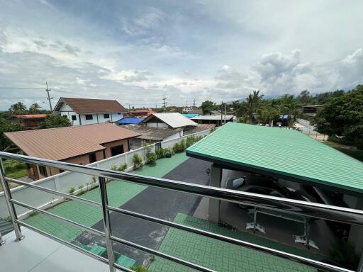 Outdoor view with rooftops, greenery, and carport