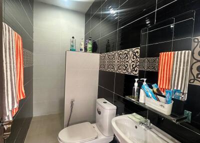 Modern bathroom with black tiled walls, a toilet, and a sink