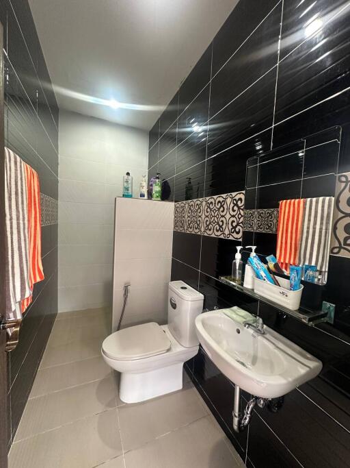 Modern bathroom with black tiled walls, a toilet, and a sink