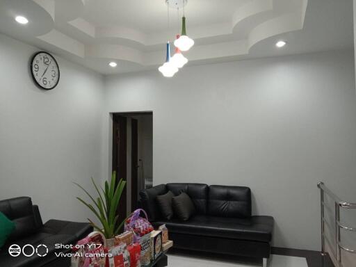 A modern living room with black leather furniture and contemporary ceiling design